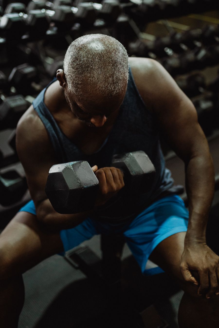 Person lifting a dumbbell while lying on a bench in a gym