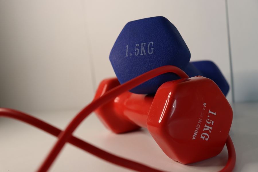 A pair of colourful dumbbells resting beside a skipping rope