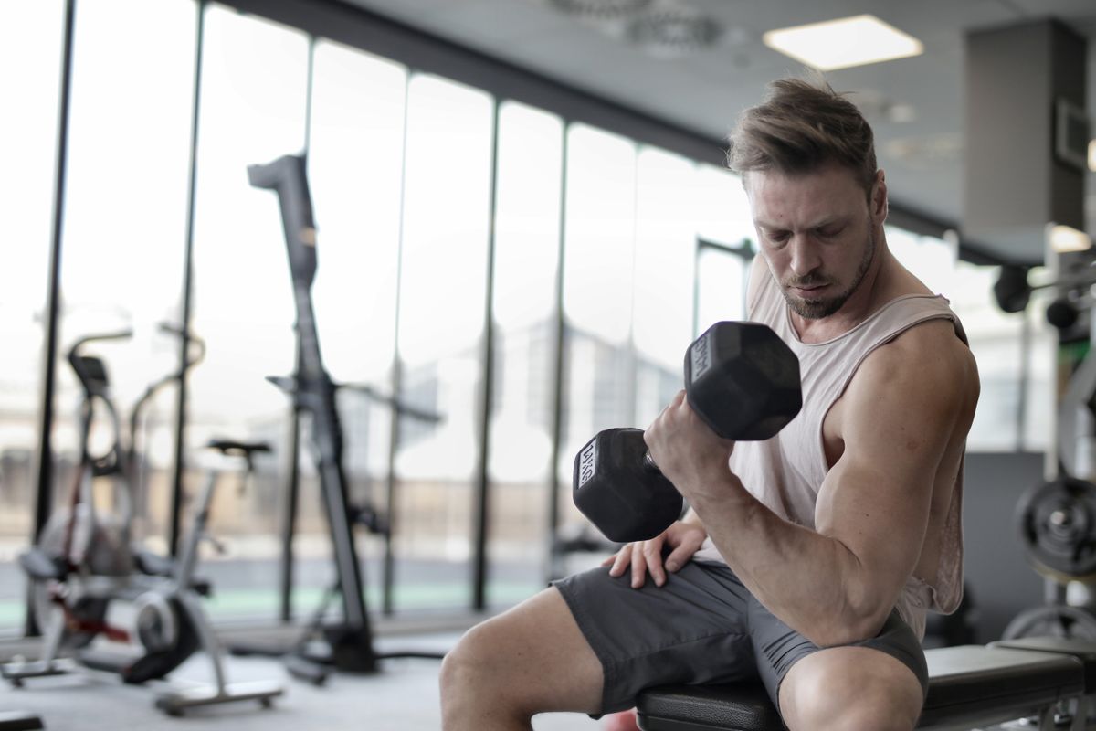 Person performing a dumbbell exercise in a gym