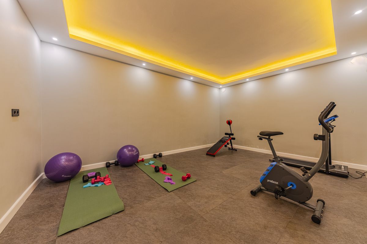 A tidy home workout space with a mat and compact equipment near a wall
