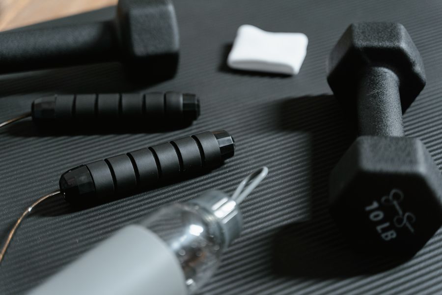 A compact home workout kit with dumbbells, a jump rope and a water bottle on a mat