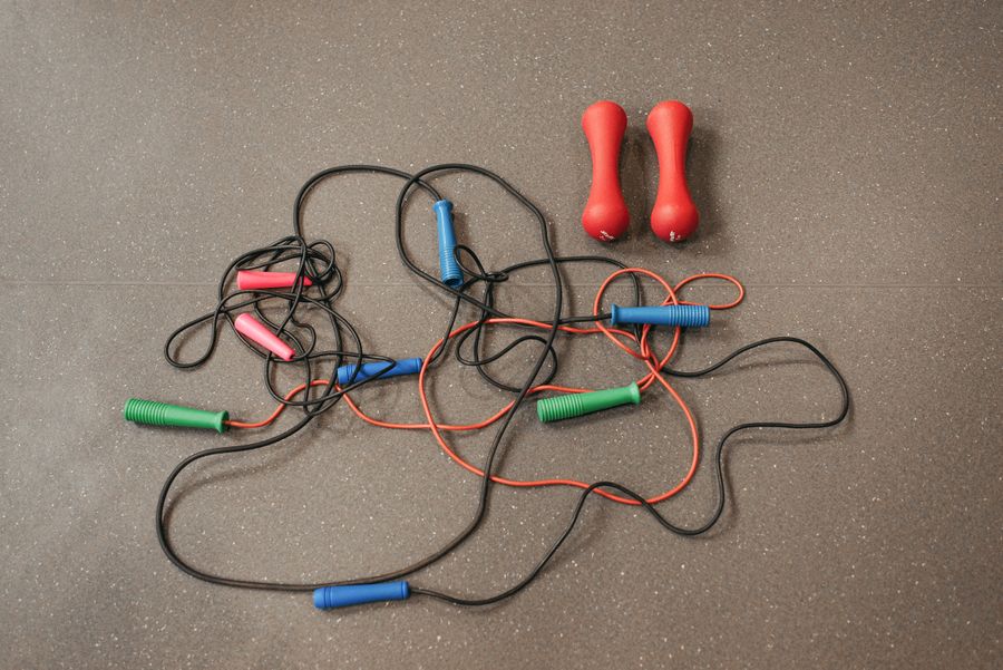Jump ropes laid beside dumbbells on a gym floor, ready for a workout