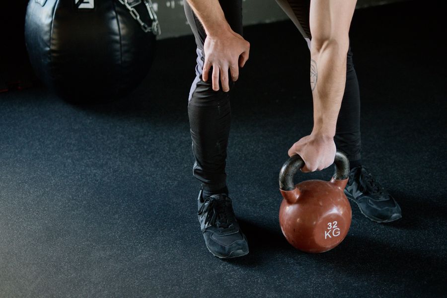 Person holding a red kettlebell in a gym, preparing to lift