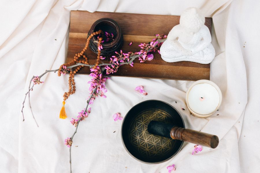 A calm meditation setup with a cushion, singing bowl and candle