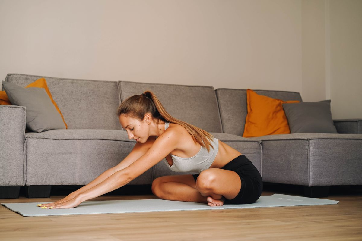 Person stretching on a yoga mat in a bright room